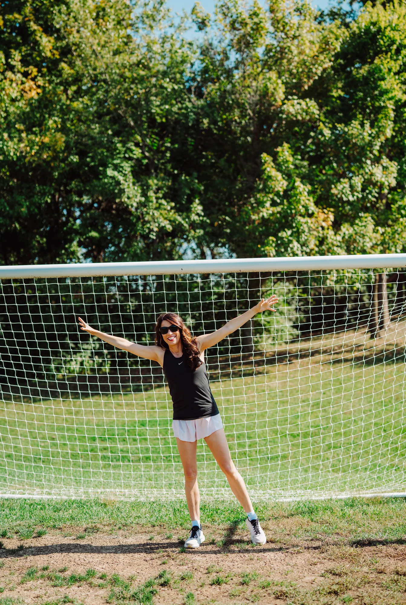 Monika celebrating with her arms up in front of a soccer goal