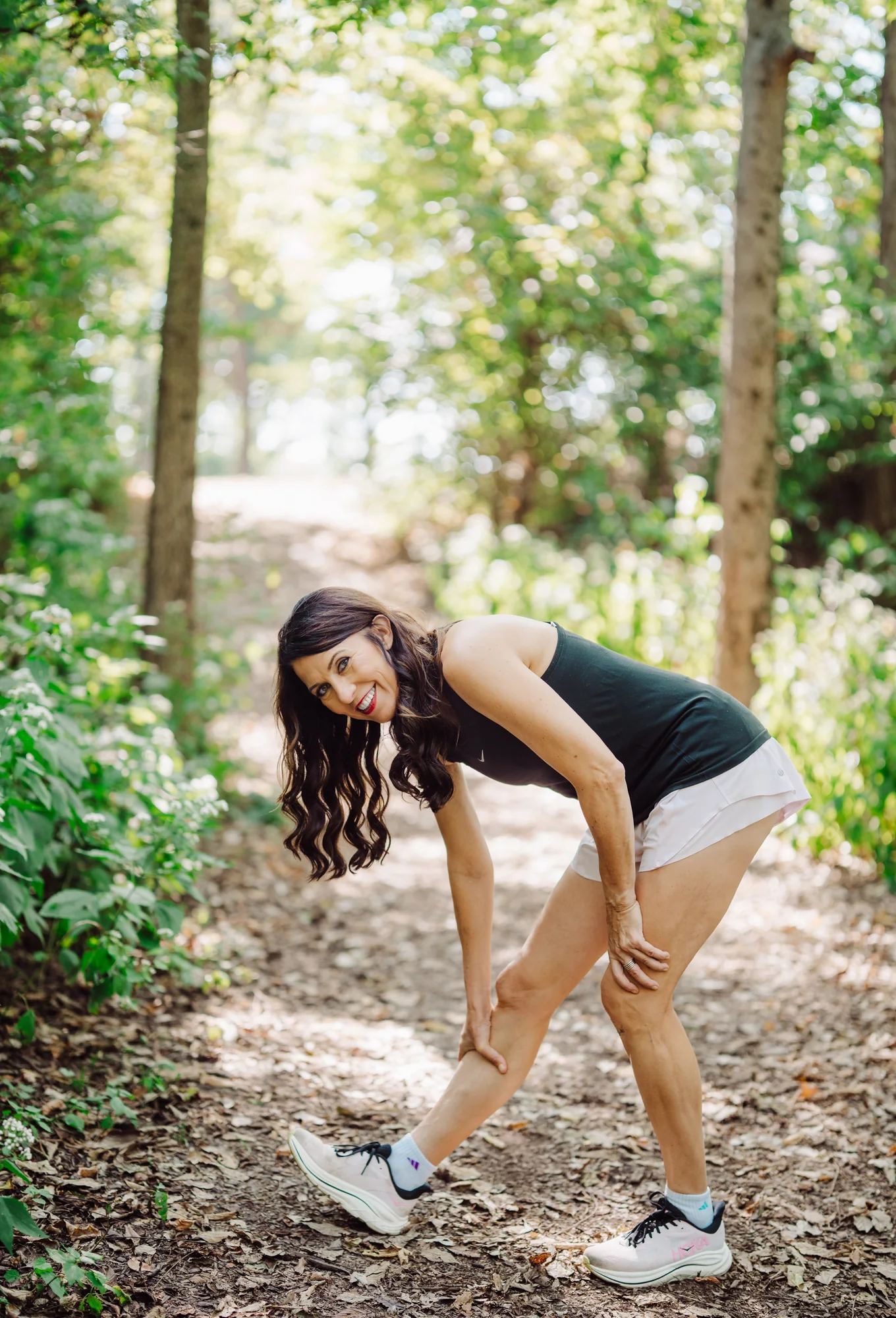 Monika tying her running shoe on a wooded trail